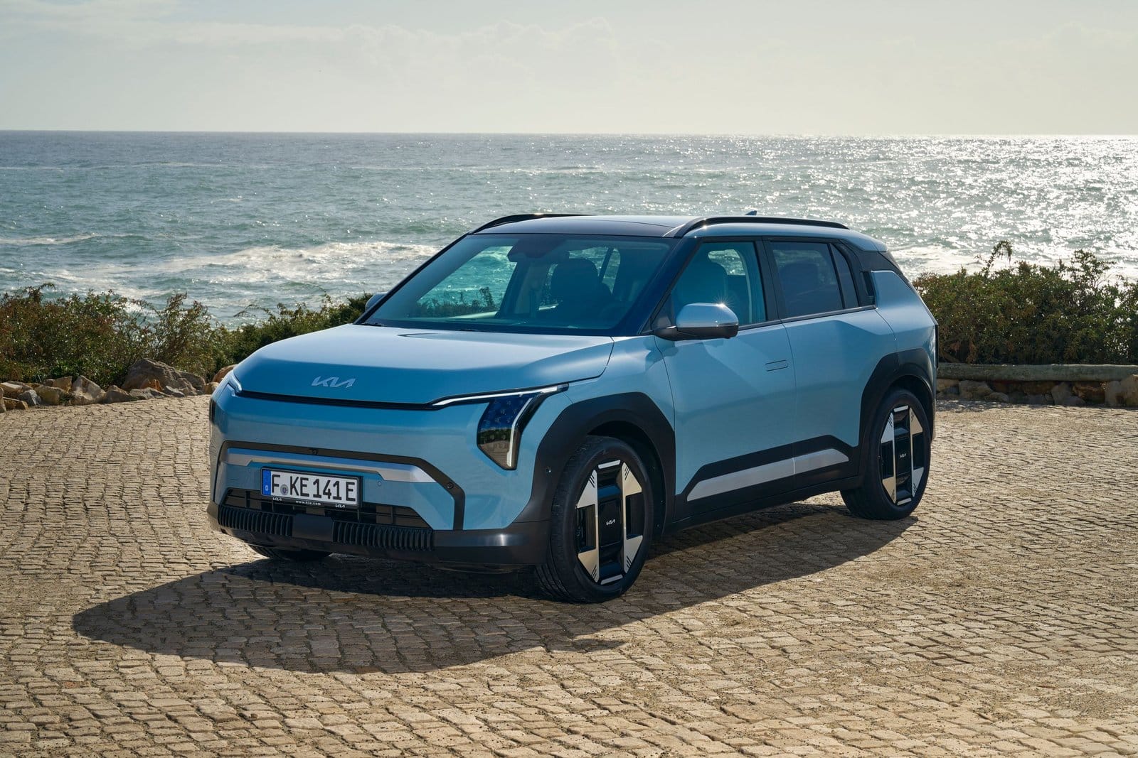 Kia EV3 electric vehicle parked near the ocean in frost blue finish