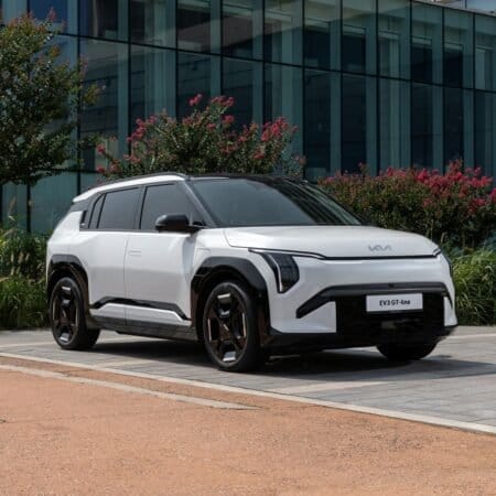 Front three-quarter view of Kia EV3 electric vehicle parked beside modern glass building