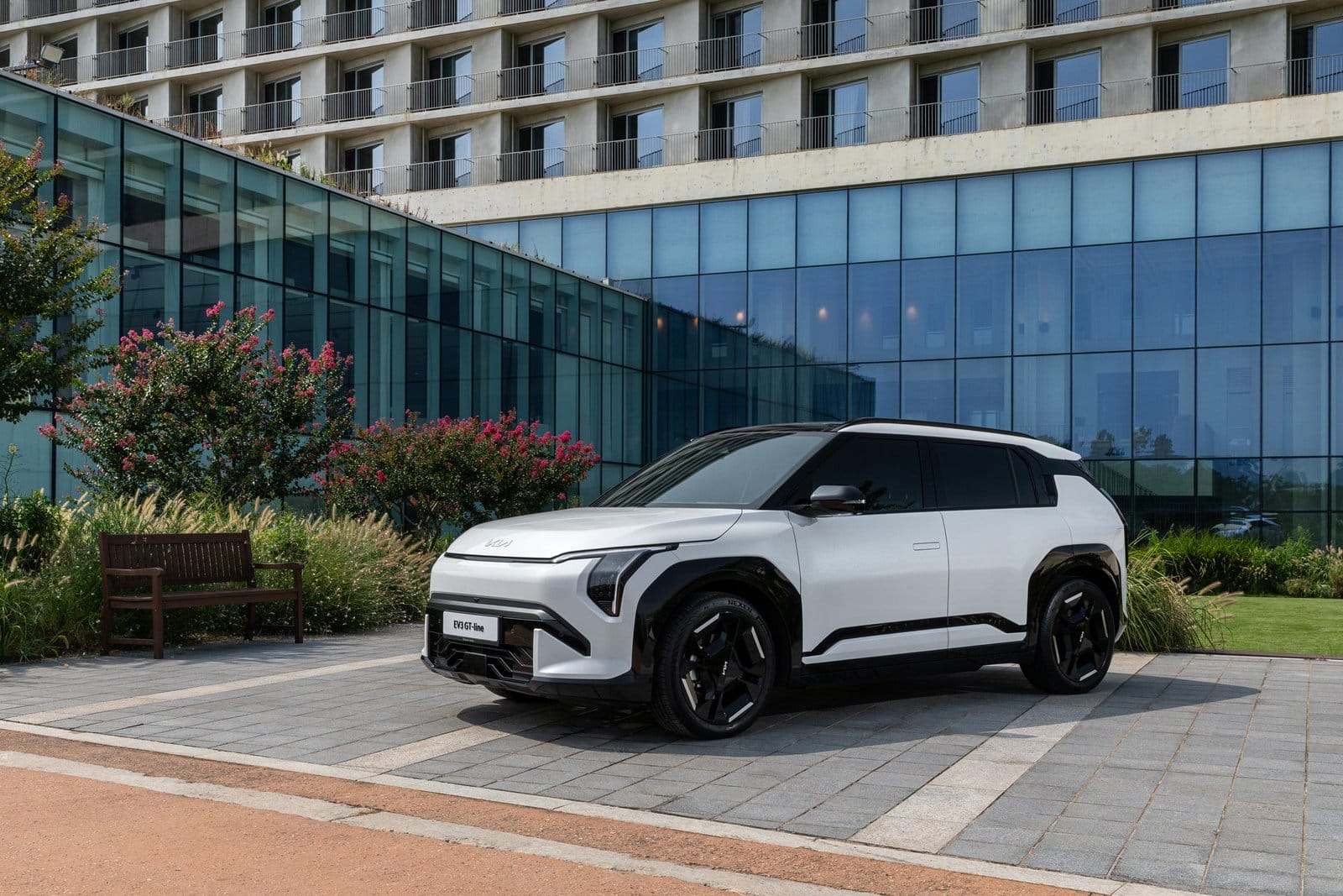 Front three-quarter exterior of Kia EV3 electric vehicle parked by modern glass building