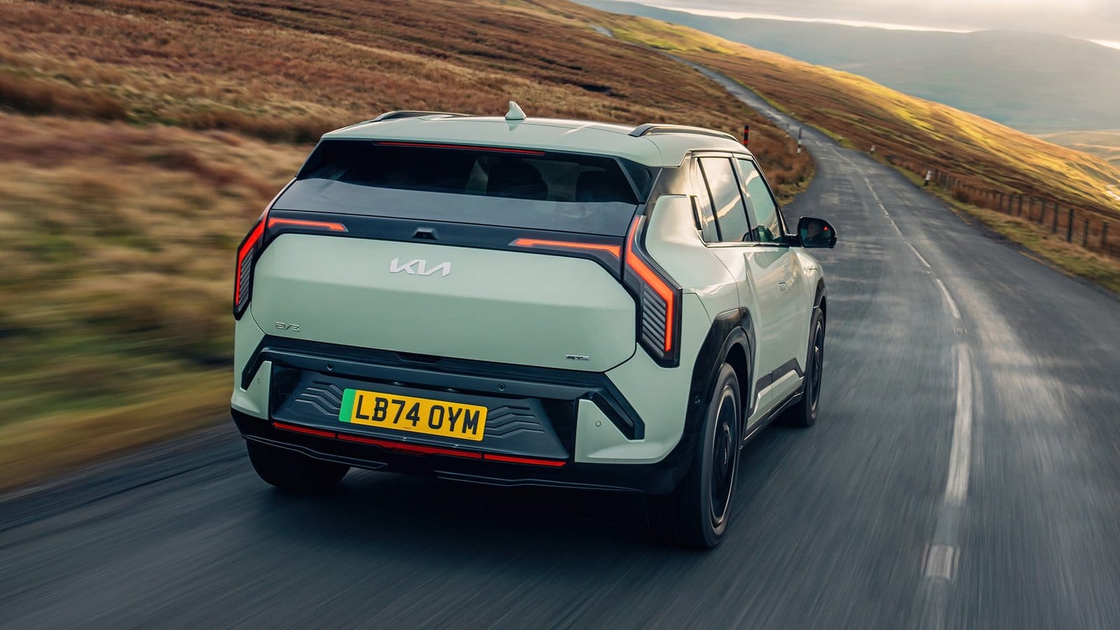 Rear view of Kia EV3 electric vehicle driving on rural road