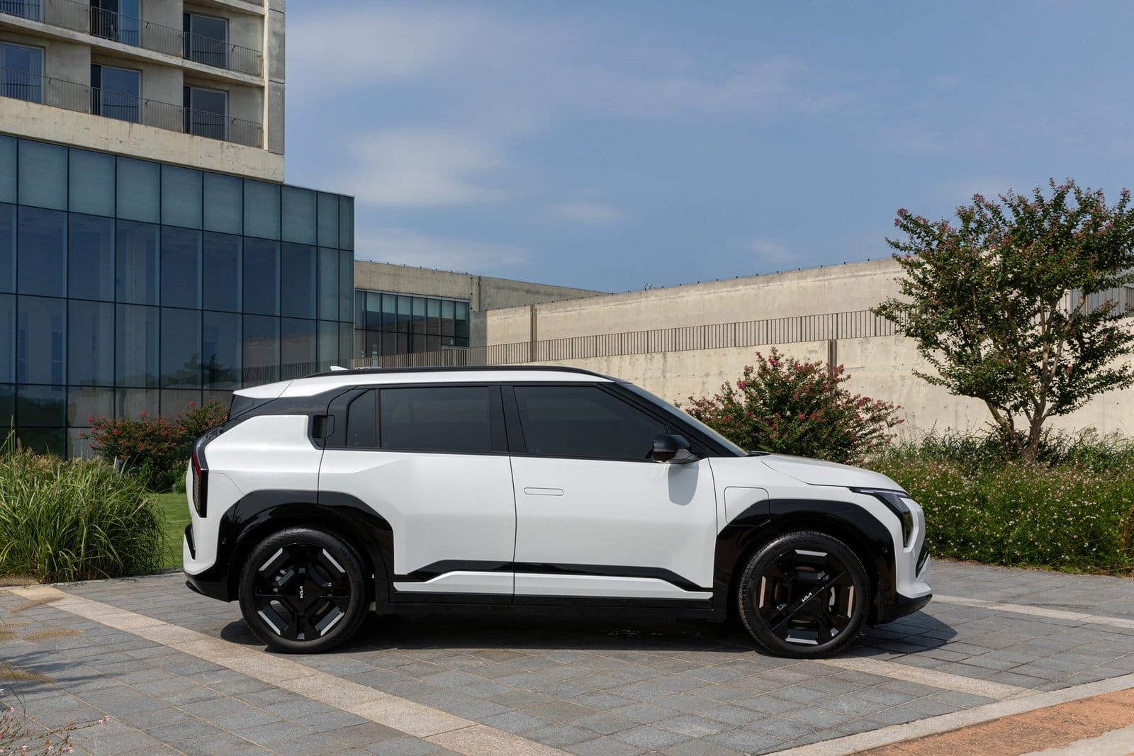 Side view of Kia EV3 electric vehicle parked near urban glass building