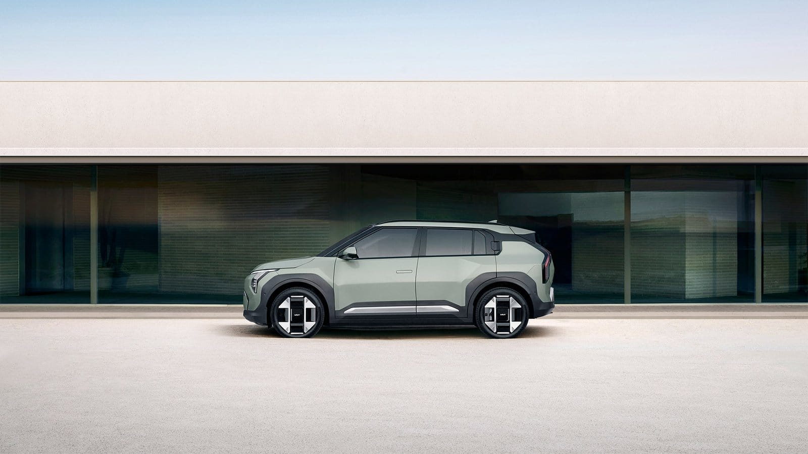 Side profile of Kia EV3 electric vehicle parked beside a glass building