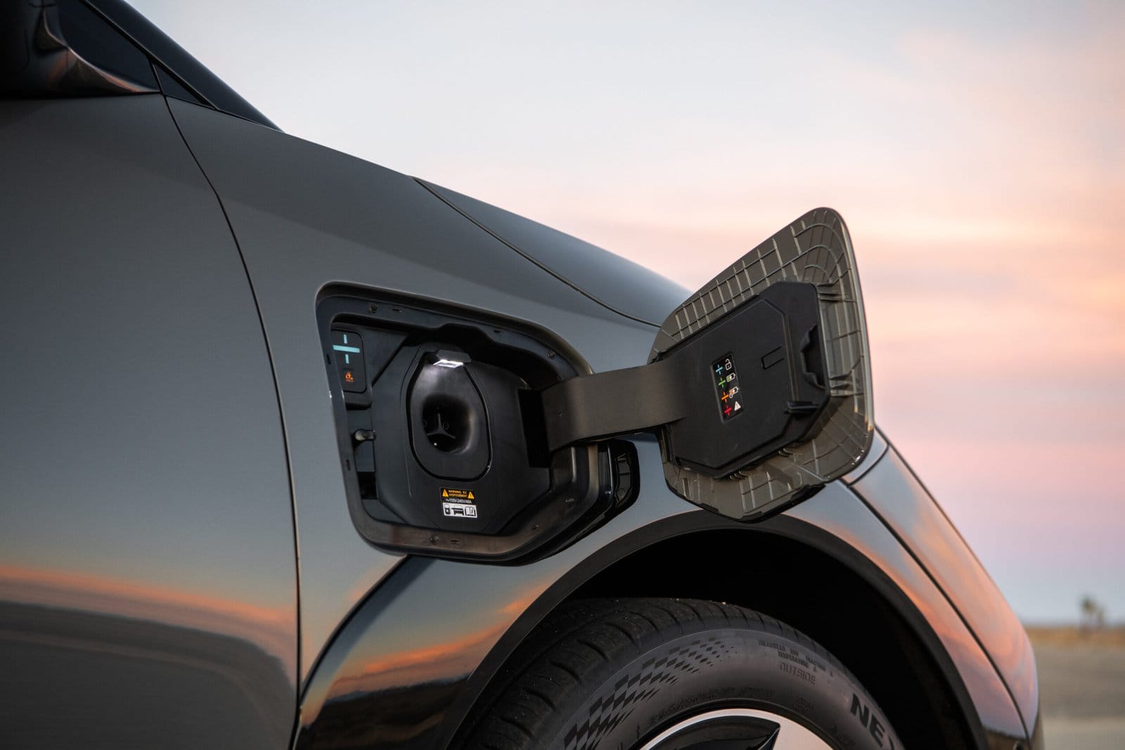 Close-up view of Kia EV4 electric vehicle charging port with the cover open at sunset