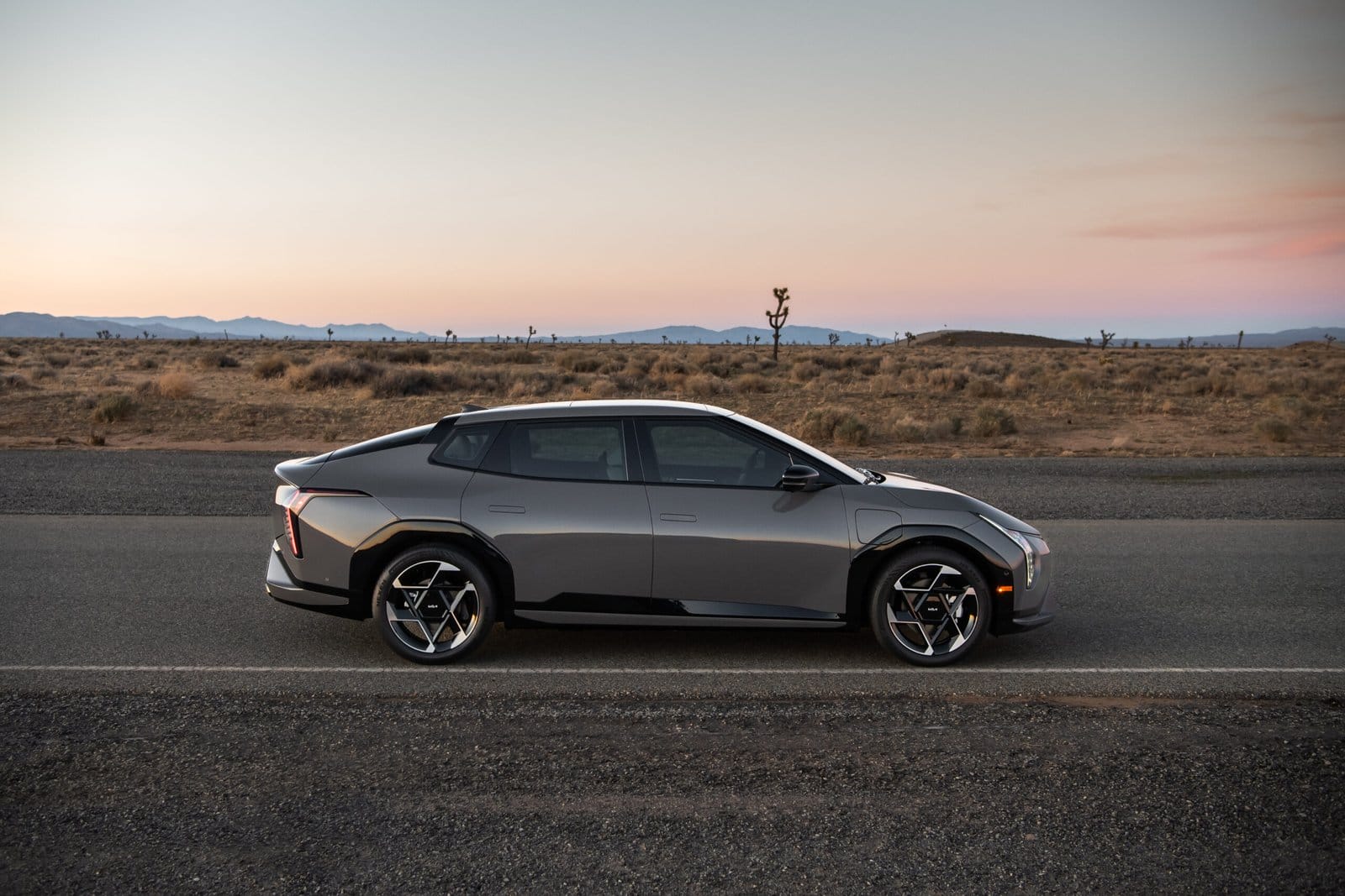 Side profile of Kia EV4 electric vehicle parked on a road in the desert at sunset
