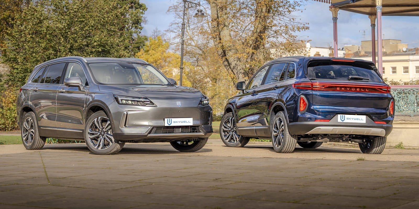 Two Skywell BE11 electric vehicle, Chinese EV models displayed together, one front view and one rear view, parked outdoors on a paved area