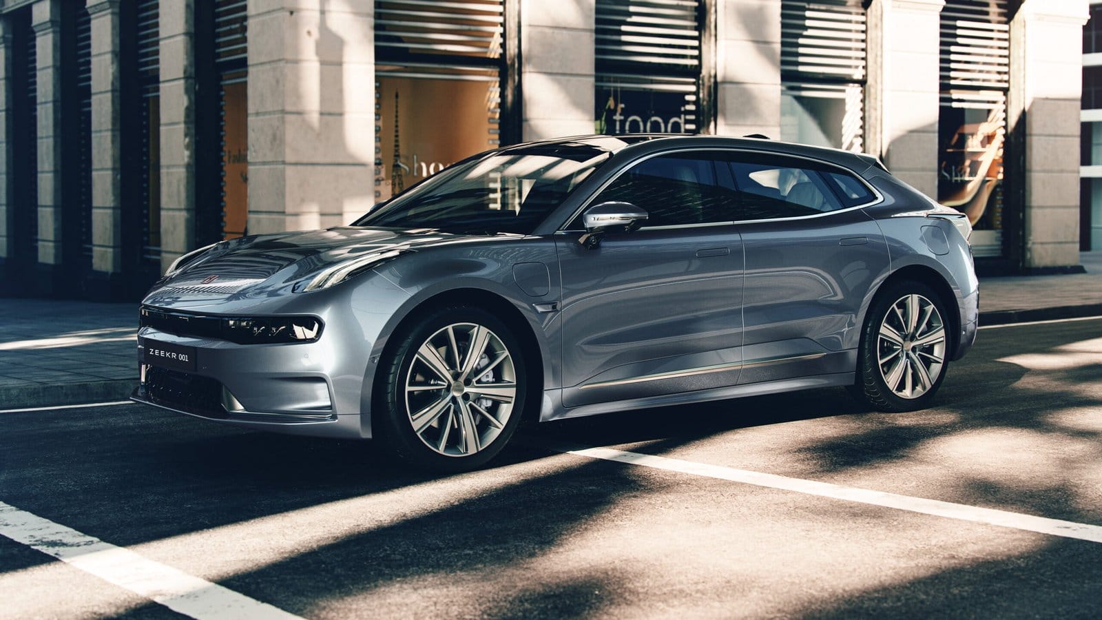 ZEEKR 001 electric vehicle, Chinese EV, parked on a sunlit city street with building shadows across the bodywork.